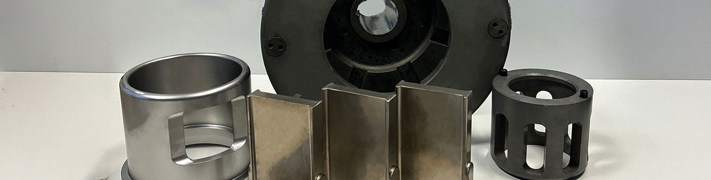 Fünf Metallteile in verschiedenen Formen auf weißem Hintergrund, glänzend und industriell.